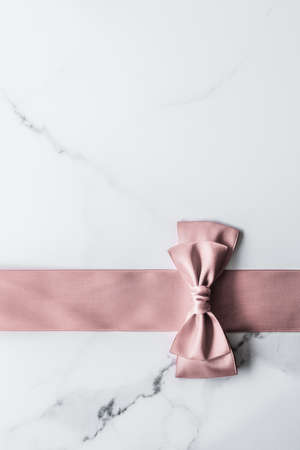 Birthday, wedding and girly branding concept - Beige silk ribbon and bow on marble background, glamour present mockup and fashion gift decoration for luxury beauty brand holiday flatlay designの写真素材