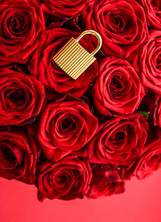 Holiday gift, flowers flatlay and happy relationship concept - Love lock for Valentines Day card, golden padlock and luxury bouquet of roses on red backgroundの写真素材