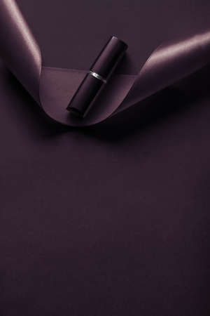 Cosmetic branding, glamour lip gloss and shopping sale concept - Luxury lipstick and silk ribbon on dark purple holiday background, make-up and cosmetics flatlay for beauty brand product designの写真素材