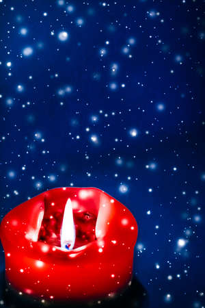 Happy holidays, greeting card and winter season concept - Red holiday candle on blue sparkling snowing background, luxury branding design for Christmas, New Years Eve and Valentines Dayの写真素材