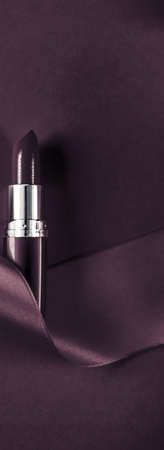 Cosmetic branding, glamour lip gloss and shopping sale concept - Luxury lipstick and silk ribbon on dark purple holiday background, make-up and cosmetics flatlay for beauty brand product designの写真素材