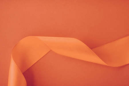 Branding, holidays and luxe brands concept - Abstract curly silk ribbon on orange background, exclusive luxury brand design for holiday sale product promotion and glamour art invitation card backdropの写真素材