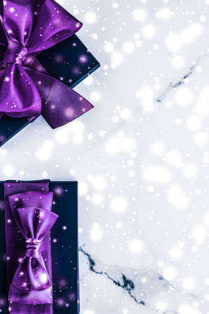 Branding, glamour and cold season concept - Winter holiday gift box with purple silk bow, snow glitter on marble background as Christmas and New Years presents for luxury beauty brand, flatlay designの写真素材