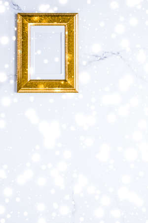 Art gallery, printable poster and online shop mockup concept - Golden photo frame and glowing glitter snow on marble flatlay background for Christmas and winter holidaysの写真素材