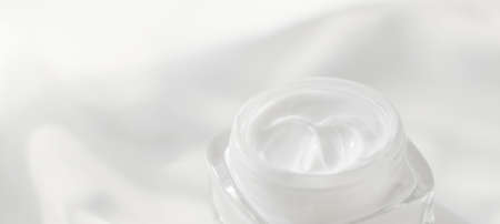 Cosmetic branding, toiletries and spf concept - Face cream moisturizer jar on silk background,...