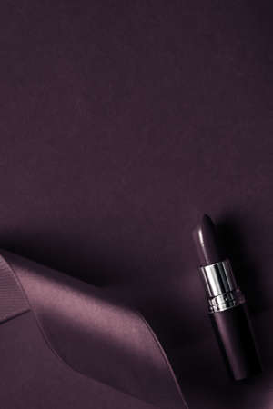 Cosmetic branding, glamour lip gloss and shopping sale concept - Luxury lipstick and silk ribbon on dark purple holiday background, make-up and cosmetics flatlay for beauty brand product designの写真素材