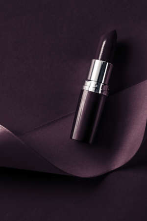 Cosmetic branding, glamour lip gloss and shopping sale concept - Luxury lipstick and silk ribbon on dark purple holiday background, make-up and cosmetics flatlay for beauty brand product designの写真素材