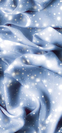 Winter fashion, shiny fabric and glamour style concept - Magic holiday blue soft silk flatlay background texture with glowing snow, luxury beauty abstract backdropの写真素材