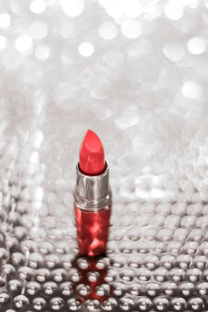 Cosmetic branding, sale and glamour concept - Coral lipstick on silver Christmas, New Years and Valentines Day holiday glitter background, make-up and cosmetics product for luxury beauty brandの写真素材