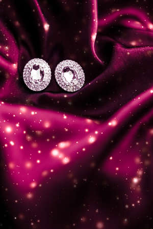 Jewellery brand, Christmas shopping and New Years gift concept - Luxury diamond earrings on dark red...