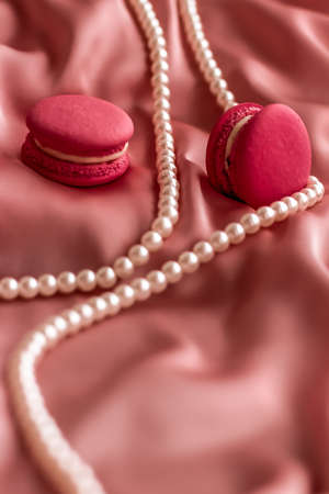 Girly, bakery and branding concept - Sweet macaroons and pearls jewellery on silk background, parisian chic jewelry, French dessert food and cake macaron for luxury confectionery brand, holiday giftの写真素材