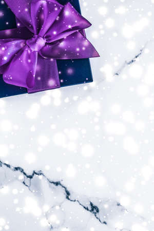 Branding, glamour and cold season concept - Winter holiday gift box with purple silk bow, snow glitter on marble background as Christmas and New Years presents for luxury beauty brand, flatlay designの写真素材