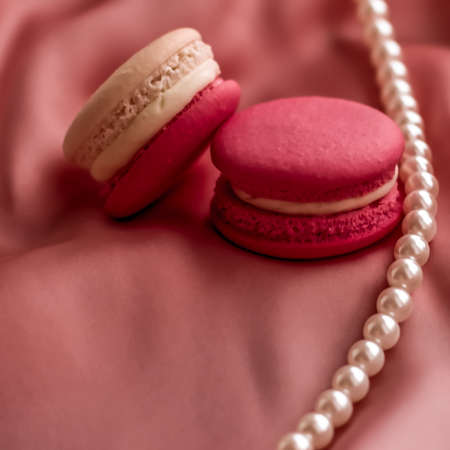 Girly, bakery and branding concept - Sweet macaroons and pearls jewellery on silk background, parisian chic jewelry, French dessert food and cake macaron for luxury confectionery brand, holiday giftの写真素材