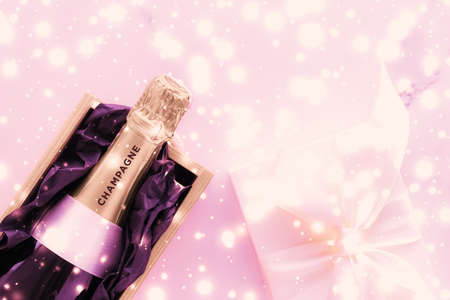 Celebration, drinks and branding concept - Champagne bottle and gift box on pink holiday glitter, New Years, Christmas, Valentines Day, winter present and luxury product packaging for beverage brandの写真素材