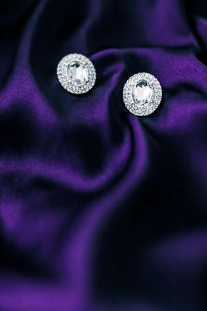 Jewellery brand, elegant fashion and bridal luxe gift concept - Luxury diamond earrings on dark violet silk fabric, holiday glamour jewelery presentの写真素材
