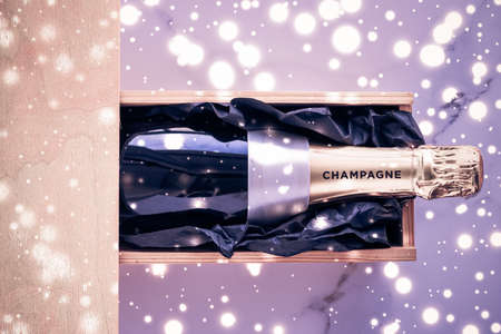 Celebration, drink and branding concept - Champagne bottle and gift box on purple holiday glitter, New Years, Christmas, Valentines Day, winter present and luxury product packaging for beverage brandの写真素材