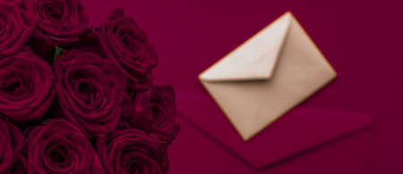 Holidays gift, floral present and happy relationship concept - Love letter and flowers delivery on Valentines Day, luxury bouquet of roses and card on maroon background for romantic holiday designの写真素材