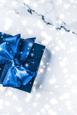 Branding, glamour and cold season concept - Winter holiday gift box with blue silk bow, snow glitter on marble background as Christmas and New Years presents for luxury beauty brand, flatlay designの写真素材