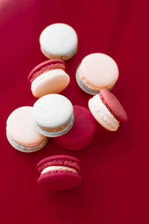 Pastry, bakery and branding concept - French macaroons on wine red background, parisian chic cafe dessert, sweet food and cake macaron for luxury confectionery brand, holiday backdrop designの写真素材