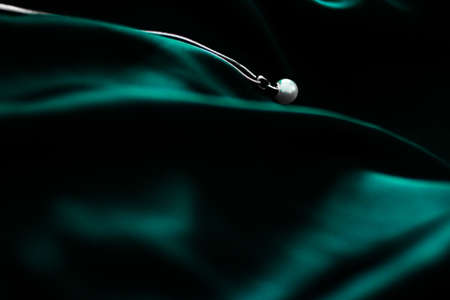 Jewellery brand, elegant fashion and bridal luxe gift concept - Luxury white gold pearl necklace on dark emerald green silk background, holiday glamour jewelery presentの写真素材