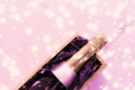Celebration, drinks and branding concept - Champagne bottle and gift box on pink holiday glitter,...