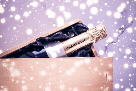Celebration, drink and branding concept - Champagne bottle and gift box on purple holiday glitter, New Years, Christmas, Valentines Day, winter present and luxury product packaging for beverage brandの写真素材