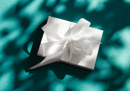 Anniversary celebration, shop sale promotion and bridal surprise concept - Luxury holiday white gift box with silk ribbon and bow on emerald green background, luxe wedding or birthday presentの写真素材
