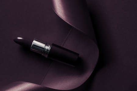 Cosmetic branding, glamour lip gloss and shopping sale concept - Luxury lipstick and silk ribbon on dark purple holiday background, make-up and cosmetics flatlay for beauty brand product designの写真素材
