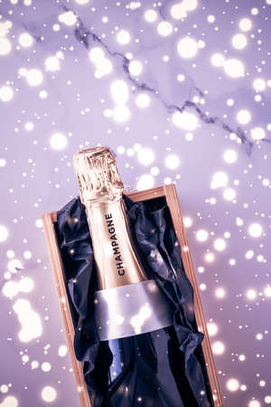Celebration, drink and branding concept - Champagne bottle and gift box on purple holiday glitter, New Years, Christmas, Valentines Day, winter present and luxury product packaging for beverage brandの写真素材
