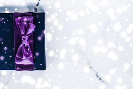 Branding, glamour and cold season concept - Winter holiday gift box with purple silk bow, snow glitter on marble background as Christmas and New Years presents for luxury beauty brand, flatlay designの写真素材