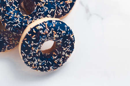 Bakery, branding and cafe concept - Frosted sprinkled donuts, sweet pastry dessert on marble table background, doughnuts as tasty snack, top view food brand flat lay for blog, menu or cookbook designの写真素材