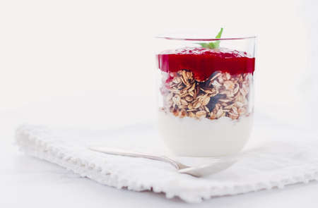 Sweet, oat and vegan concept - Homemade granola parfait with berry jam and mint, yogurt and muesli cereal as healthy breakfast food in the morning, organic dairy yoghurt for diet nutrition brandの写真素材