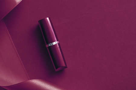 Cosmetic branding, glamour lip gloss and shopping sale concept - Luxury lipstick and silk ribbon on plum holiday background, make-up and cosmetics flatlay for beauty brand product designの写真素材