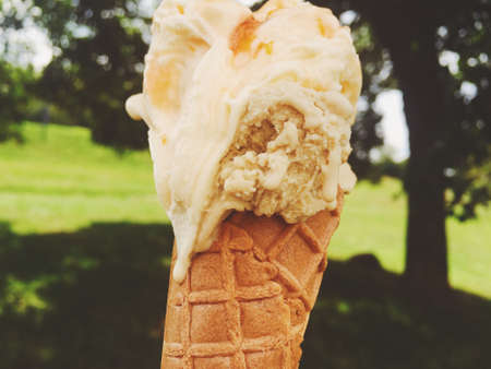 Delicious gelato, organic dairy and homemade recipe concept - Ice cream cone melting outdoors in...