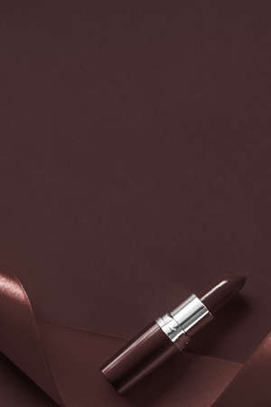Cosmetic branding, glamour lip gloss and shopping sale concept - Luxury lipstick and silk ribbon on chocolate holiday background, make-up and cosmetics flatlay for beauty brand product designの写真素材