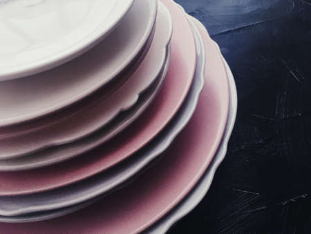 Stack of clean empty plates on black background, luxe dishware and table decor