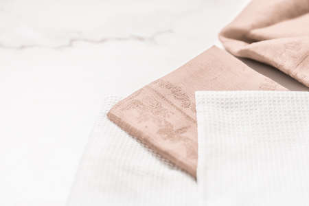 Folded napkin and kitchen towel set on white marble background, table decor concept