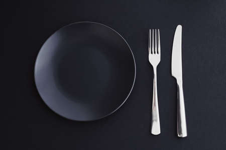 Empty plates and silverware on black background, premium tableware for holiday dinner, minimalistic design and diet conceptの写真素材