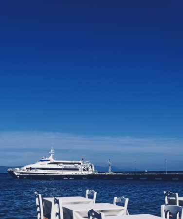 Kos Island, Greece circa May 2020: Empty restaurant by the Aegean sea and cruise boatのeditorial素材