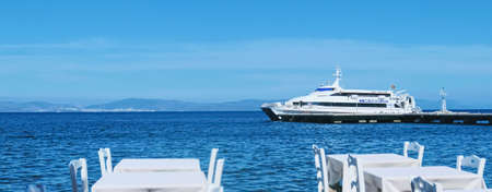 Kos Island, Greece circa May 2020: Empty restaurant by the Aegean sea and cruise boatのeditorial素材