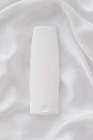 Blank label cosmetic container bottle as product mockup on white silk background, hygiene and...