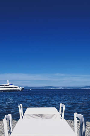 Empty restaurant by the Aegean sea and cruise boat, travel and nature, sceneの写真素材