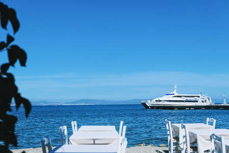 Kos Island, Greece circa May 2020: Empty restaurant by the Aegean sea and cruise boatのeditorial素材