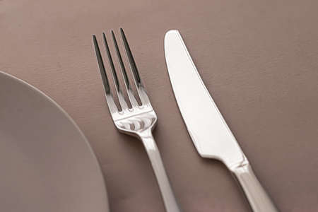 Empty plate and cutlery as mockup set on brown background, top tableware for chef table decor and menu branding designの写真素材