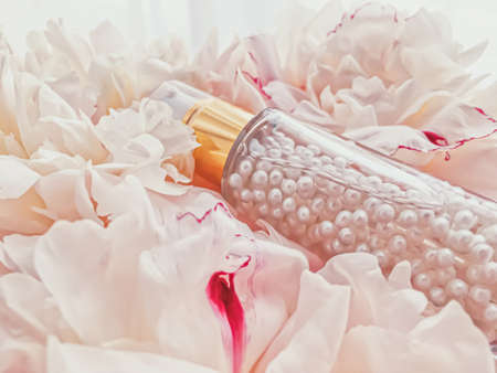 Luxurious cosmetic bottle as antiaging skincare product on background of flowers, blank label packaging for body care branding designの写真素材