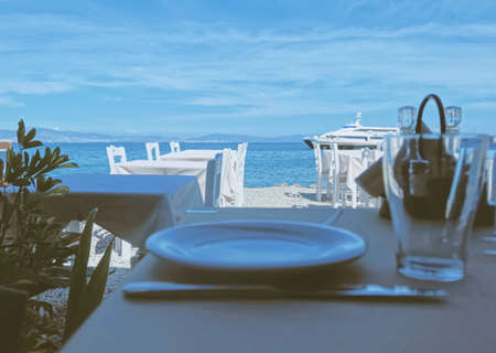 Kos Island, Greece circa May 2020: Empty restaurant by the Aegean sea and cruise boatのeditorial素材