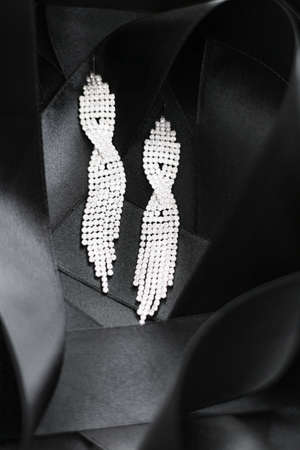 Luxury diamond earrings on black silk ribbon as background, jewelry and fashion brandsの写真素材