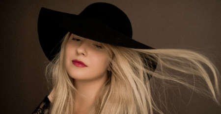 Classy blonde woman wearing a hat, artistic film portrait for fashion campaign and beauty brand designの写真素材