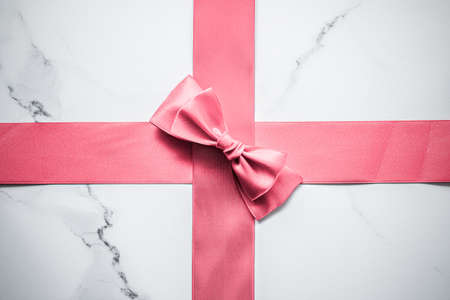Birthday, wedding and girly branding concept - Coral silk ribbon and bow on marble background, girl...