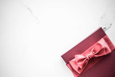 Birthday, wedding and girly branding concept - Coral gift box with silk bow on marble background, girl baby shower present and glamour fashion gift for luxury beauty brand, holiday flatlay art designの写真素材